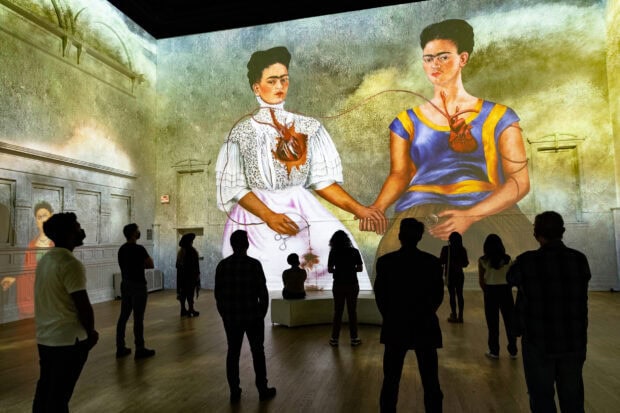 People observing a large Frida Kahlo art installation inside a gallery with high definition details