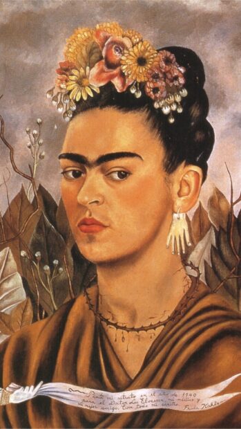 A portrait of Frida Kahlo wearing floral headpiece and unique hand earrings