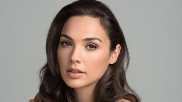 Close up of Gal Gadot with natural makeup and wavy hair in a studio setting