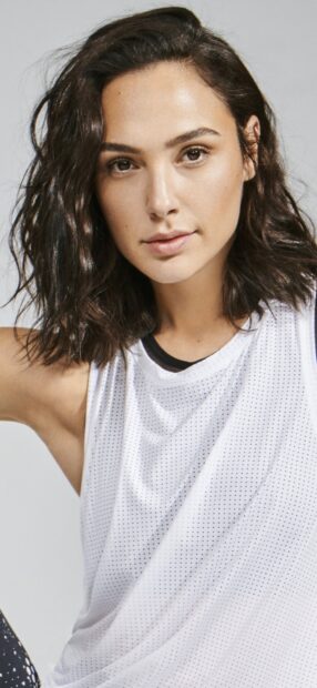Gal Gadot wearing a white sleeveless top posing with a neutral expression in a close up portrait