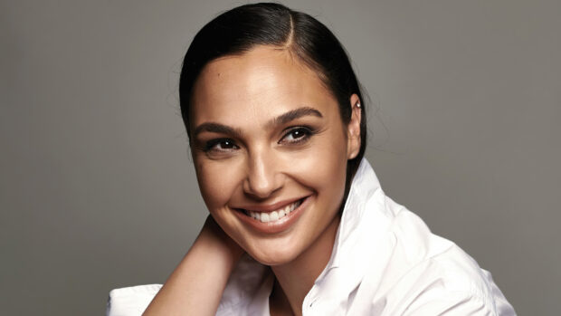 Gal Gadot smiling brightly with slicked back hair wearing a white shirt