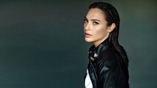 Gal Gadot wearing a black leather jacket posing against a dark background