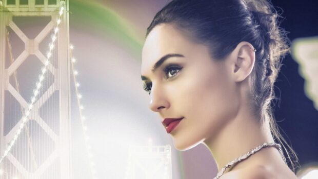 Gal Gadot with elegant makeup and necklace looking right with illuminated bridge background