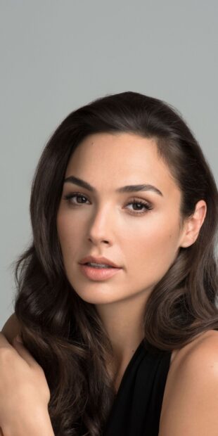 Gal Gadot with natural makeup and long dark hair looking at the camera in a close up portrait