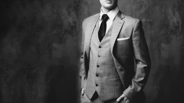 A man in a stylish suit and tie posing confidently with hands in pockets