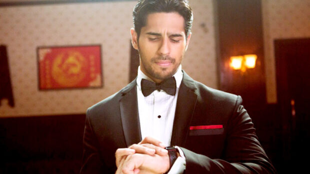 Gentleman checking watch in a suit and bow tie indoors with formal attitude