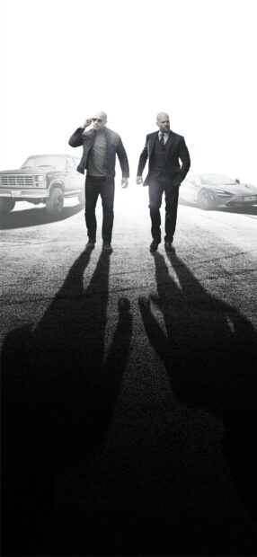 Two gentlemen walking on the road with shadows and cars in the background