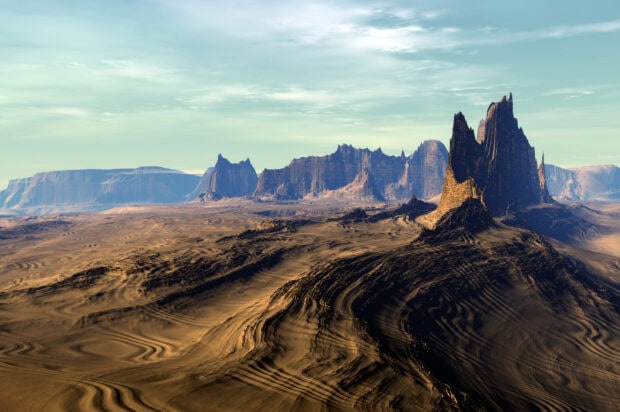 Vast desert landscape with unique mountain formations under a cloudy sky showcasing natural geography features