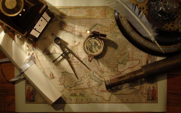 Antique map with compass divider and telescope on wooden table