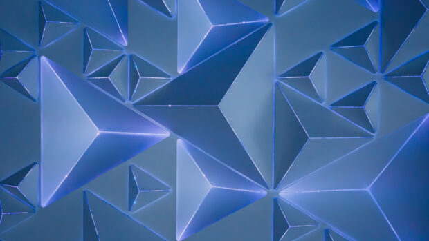 Blue three dimensional geometric shapes forming a pattern of pyramids and prisms in digital art