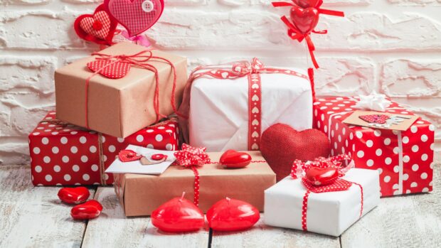 Red and white wrapped gifts with decorative hearts on wooden surface for gifts