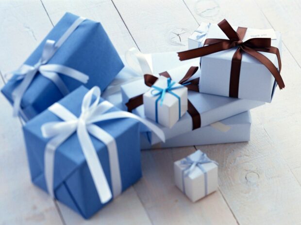 Blue and white gift boxes with ribbons arranged on a wooden floor