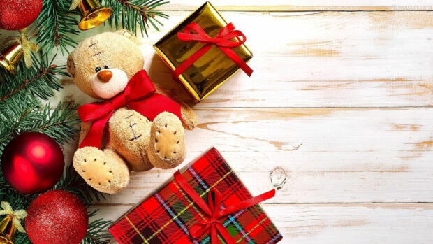 A cute teddy bear with gifts and Christmas decorations on wooden surface