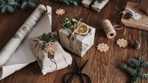 Rustic wrapping paper with natural decorations and festive gifts on wooden table
