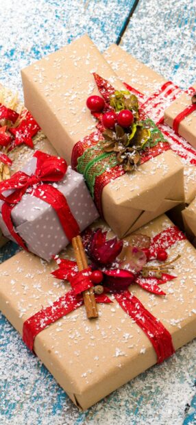 Christmas gifts decorated with ribbons and natural ornaments on a snowy surface