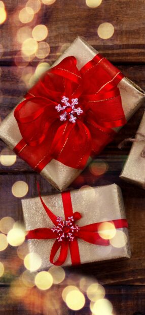 Elegant gift boxes wrapped with red ribbons and festive decorations on wooden surface