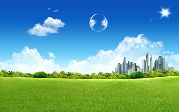 A green field and trees with city skyline under a clear blue sky with clouds and bubbles