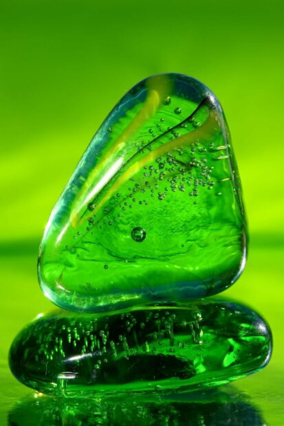 A close up of green glass stones with bubbles on a green surface
