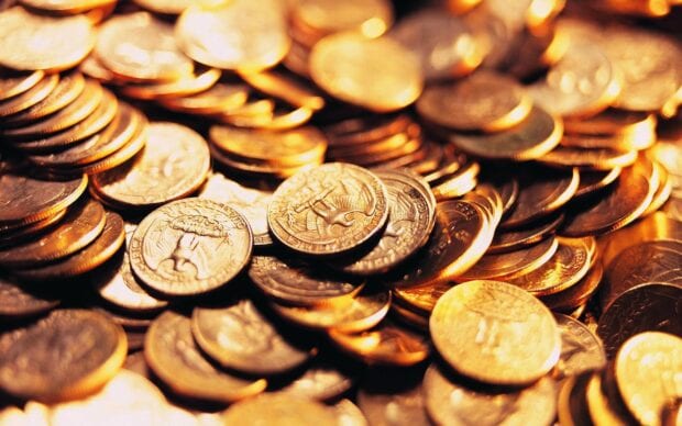 A close up of gold coins stacked and scattered in warm lighting