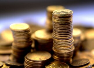 A close up view of stacked gold coins with a blurred background showing gold coins