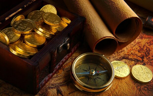 A treasure chest filled with gold coins and a compass on an antique map with rolled parchment scrolls