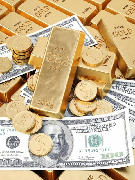 Stacks of gold coins and gold bars placed on top of US dollar bills