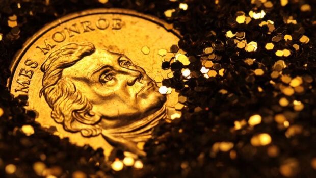 A close up of gold coins surrounded by shimmering golden particles