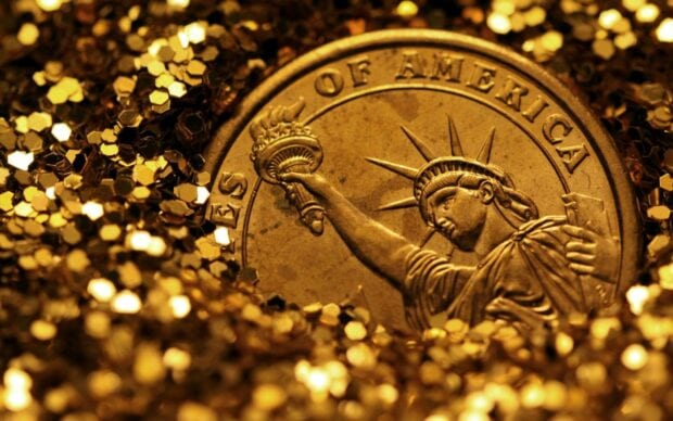 A close up of gold coins featuring the Statue of Liberty design surrounded by shimmering decorations
