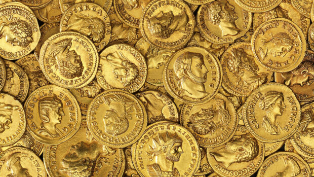 Ancient gold coins with detailed engravings stacked closely together