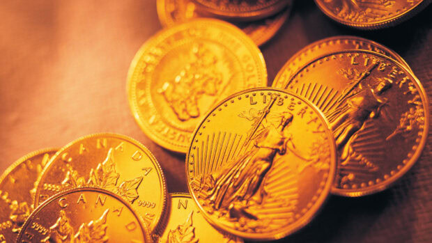 Close up of gold coins with intricate designs showing liberty and maple leaves