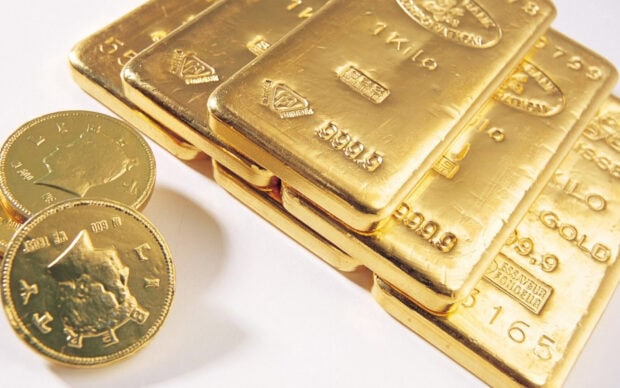Gold bars and coins stacked together showing the value of gold coins