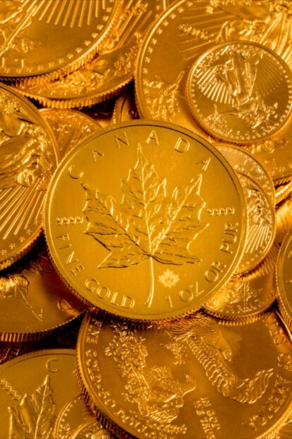 A close up of gold coins featuring a maple leaf design and fine gold inscriptions