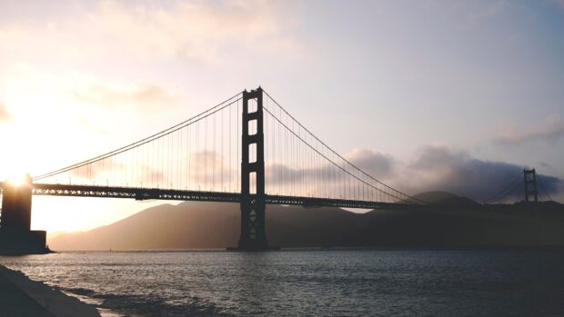 Golden Gate Bridge silhouette during sunset with mountains in the background