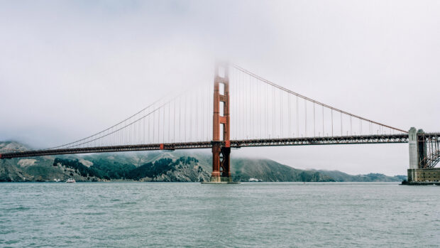 Golden Gate Bridge with fog covering the top of the tower over the bay waters