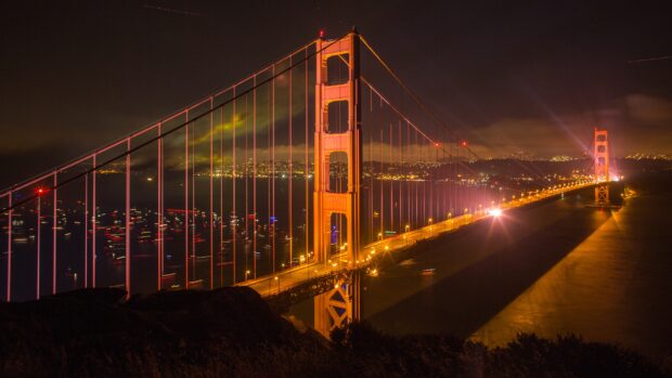 Golden Gate Bridge lit up at night with city lights in the background