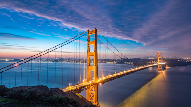 Golden Gate Bridge at dusk with city lights glowing in the background