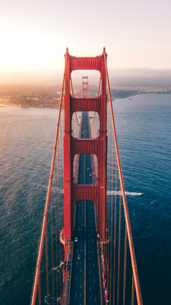Aerial view of Golden Gate Bridge with cars crossing over the water at sunset