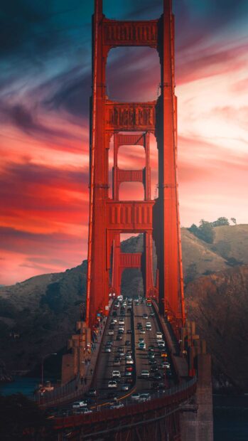 The Golden Gate Bridge with heavy traffic under a vibrant sunset sky