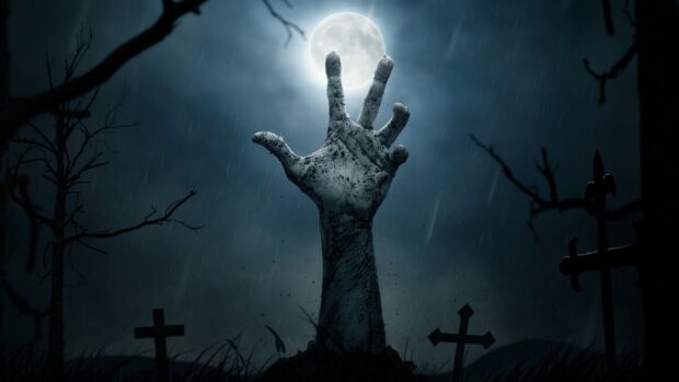 Gothic art hand rising from grave under full moon in a dark rainy cemetery