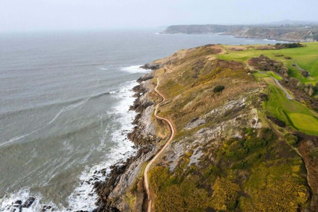 A winding coastal path along the rocky cliffs of Gower Peninsula surrounded by rugged terrain and the sea