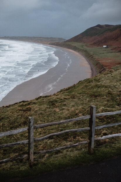 A scenic view of a coastal landscape with waves and grassy cliffs on Gower Peninsula