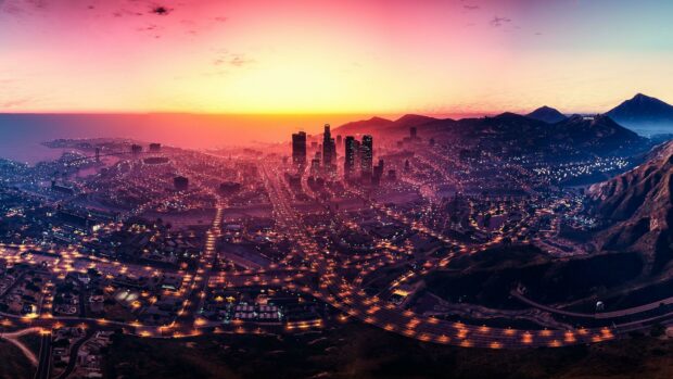 Grand Theft Auto 5 cityscape at sunset with glowing lights and mountains in the background