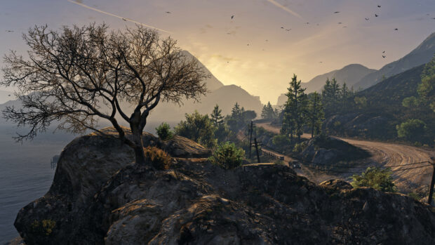 A barren tree on rocky hill overlooking a winding dirt road in Grand Theft Auto 5
