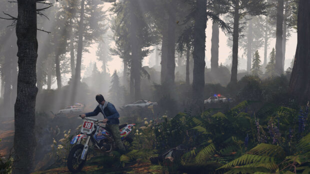A man on a dirt bike in forest with police cars in the background in Grand Theft Auto 5