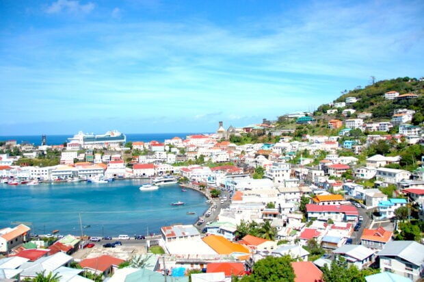 A vibrant cityscape of Grenada with colorful buildings by the blue sea under a clear sky