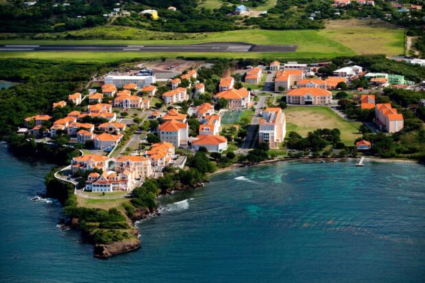 Aerial view of Grenada showing coastal buildings with orange roofs and green landscape