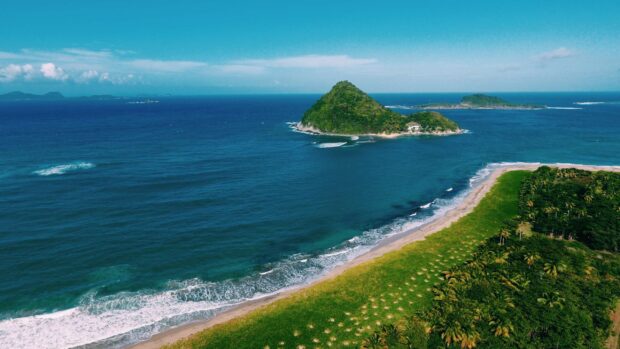 A scenic view of Grenada island with lush greenery and ocean waves along the coastline