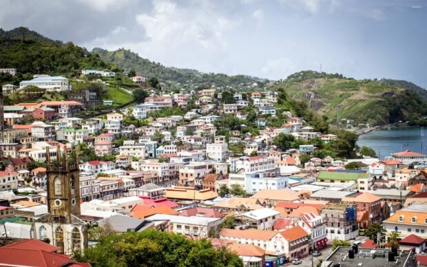 Colorful hillside townscapes in Grenada with a historic church tower and lush green hills