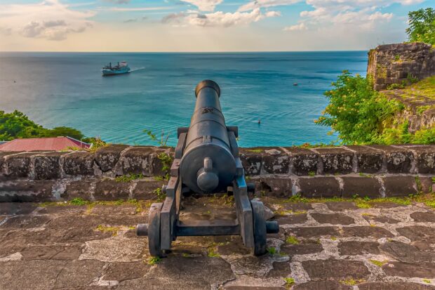 Historic cannon overlooking the sea and ship in Grenada coastline