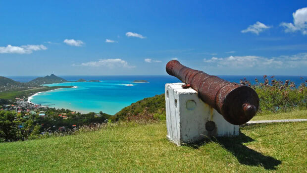 Old cannon overlooking the scenic Grenada coastline and turquoise sea on a sunny day